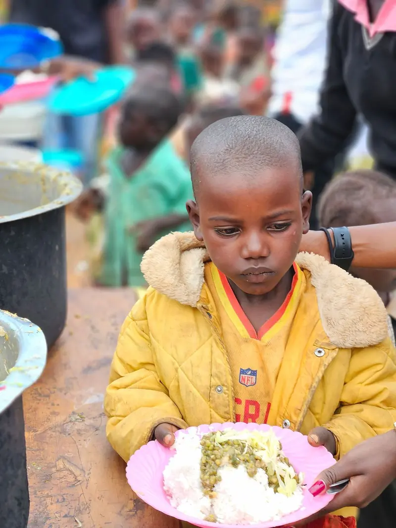 A boy holding his plate at a Lishe Kwa Mtoto school meal
