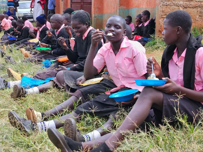 Children sitting on the grass enjoying a school meal together