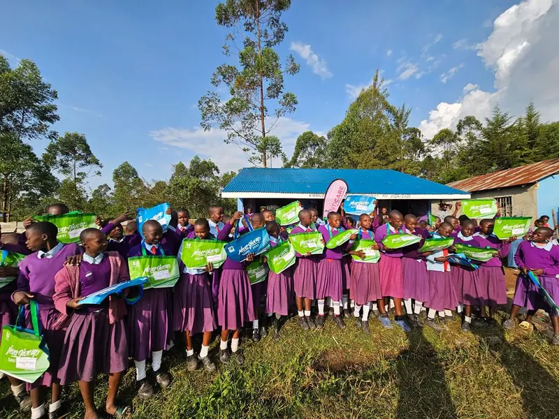 Girls in school uniform celebrating with their menstrual health kits