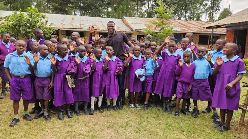 Learners in new school uniforms waving to the camera after a Uniform a Child distribution