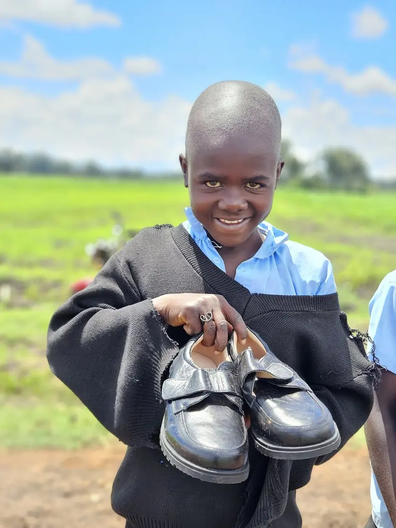 A boy proudly holding his new pair of school shoes