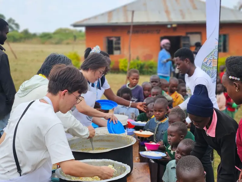 Volunteers ladling a warm meal for children at a Lishe Kwa Mtoto feeding day